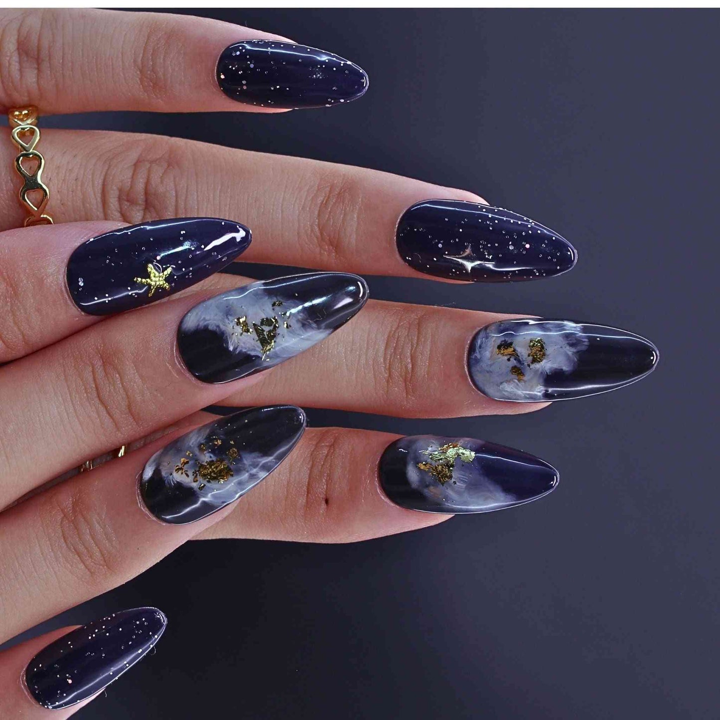 Hand with dark nail polish featuring celestial by Tennail.