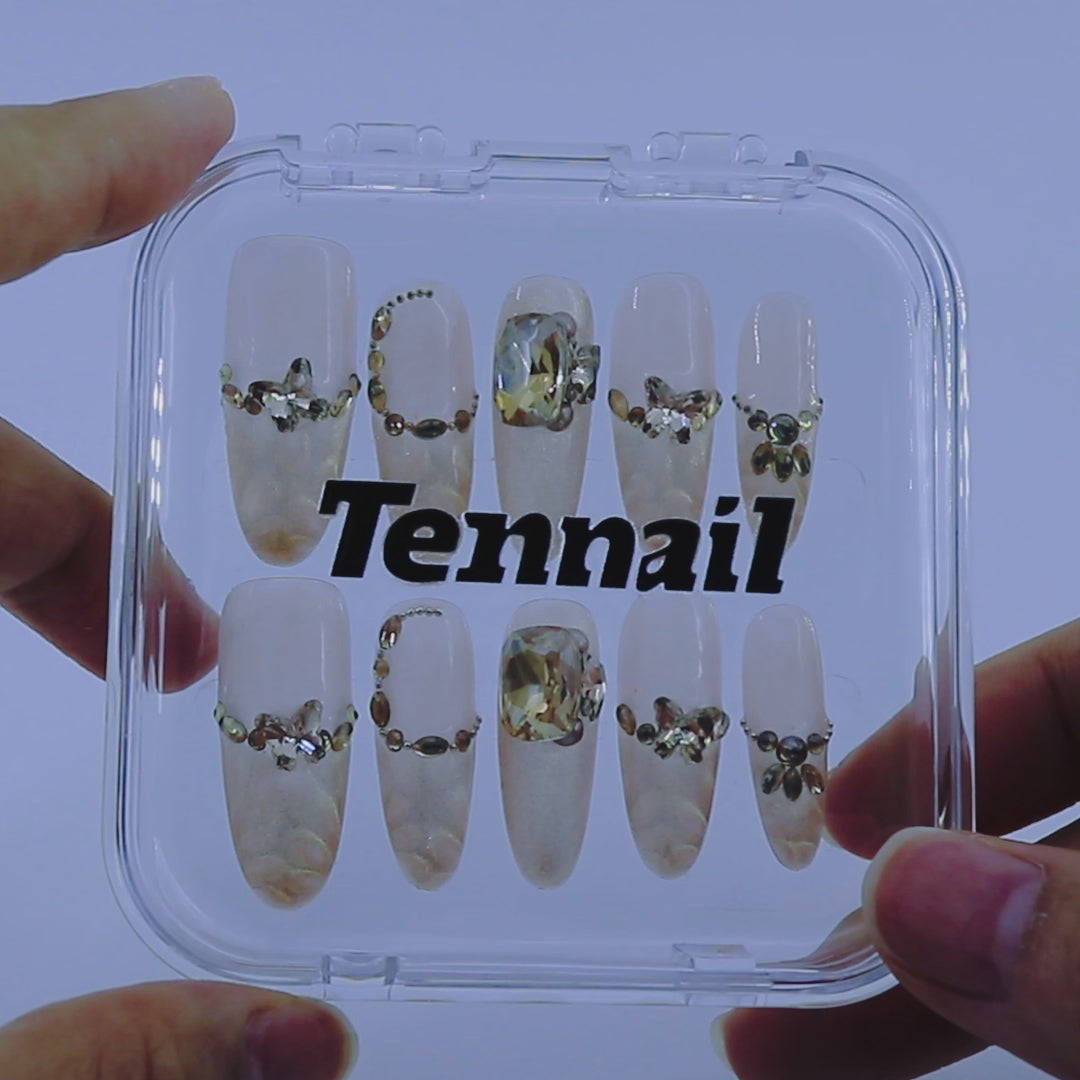 Video shows TenNail's Aurora Gilded Nails: Long oval press - ons with shimmering gold, delicate metal chains, and sparkling gems shimmer as hands move, lending a luxurious, glowing touch to any style.