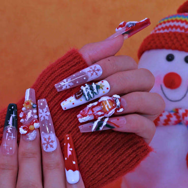 Nail art with Christmas designs on a hand wearing a red sweater, with a snowman in the background. by Tennail press on nails.