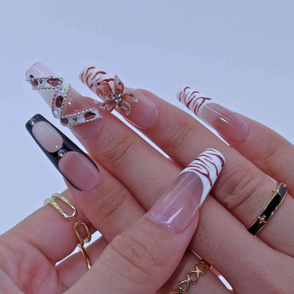 Close-up of a hand with intricately designed nails and gold rings on a light background by Tennail press on nails.