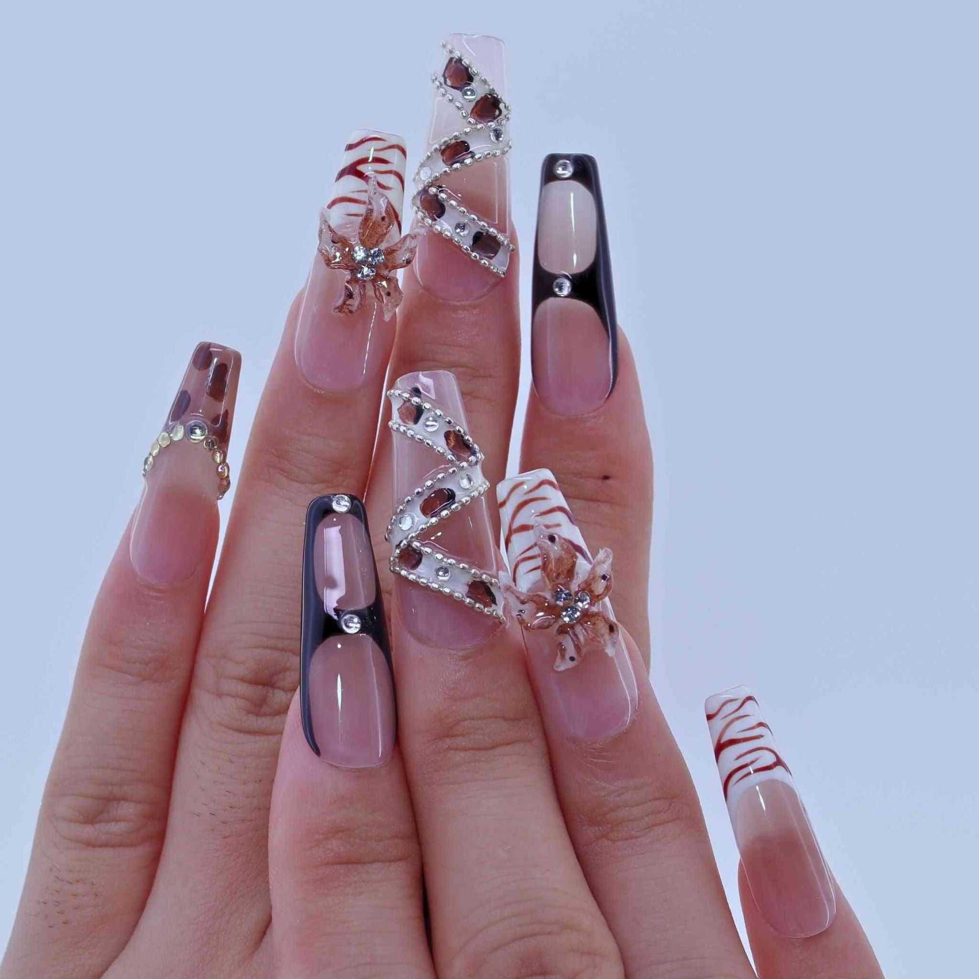 Manicured nails with various decorative designs on a plain background by Tennail press on nails.
