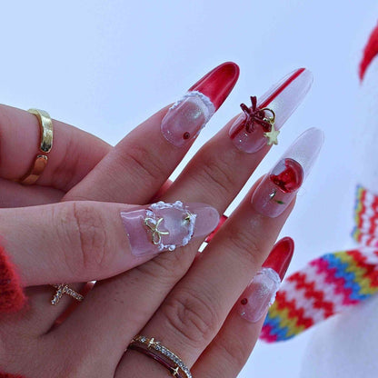 Close-up of hands with red and clear acrylic nails decorated with gold stars and red rhinestones.by Tennail press on nails.