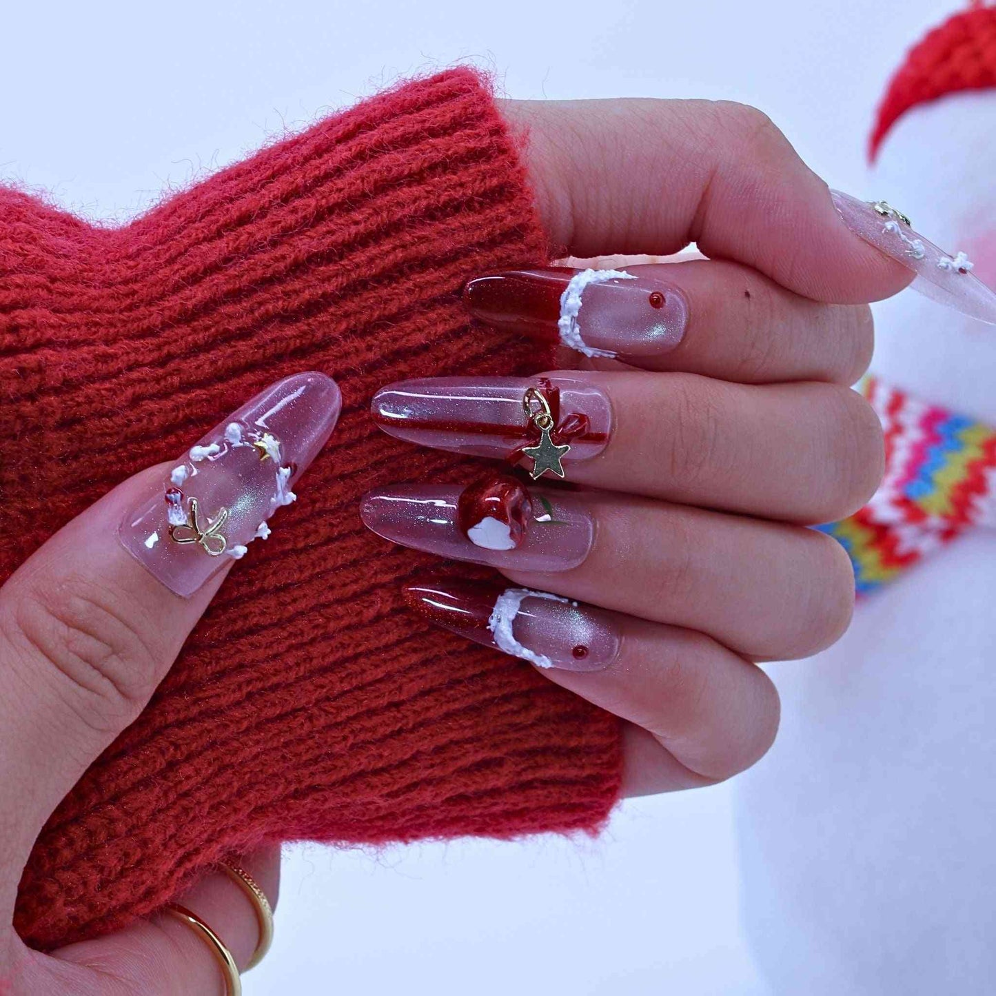 Close-up of a hand with decorative nails wearing red gloves against a white background by Tennail press on nails.