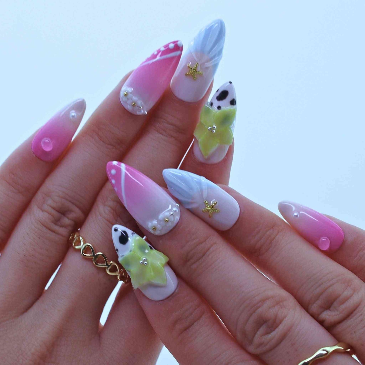 Hand with pink and white nail art on a light blue background