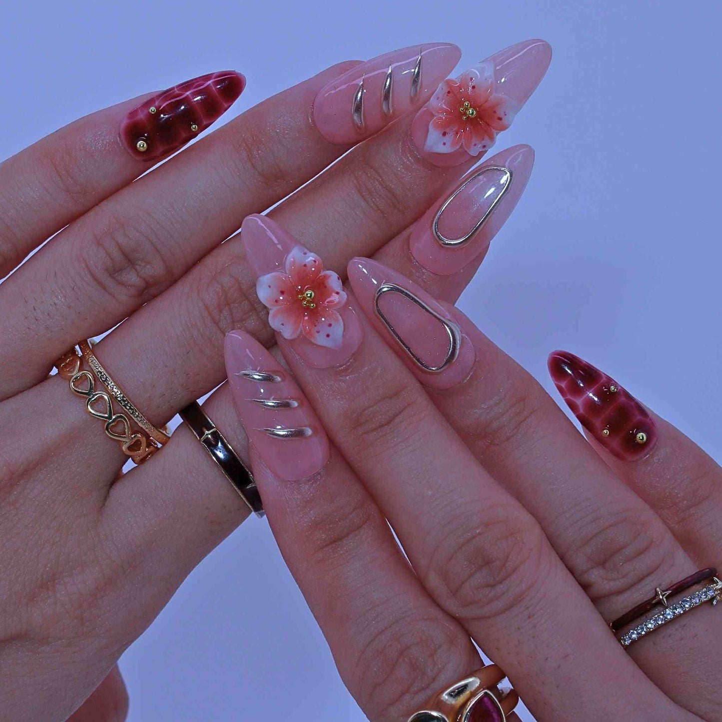 Close-up of a hand with decorative nails and rings on a blurred background by Tennail.