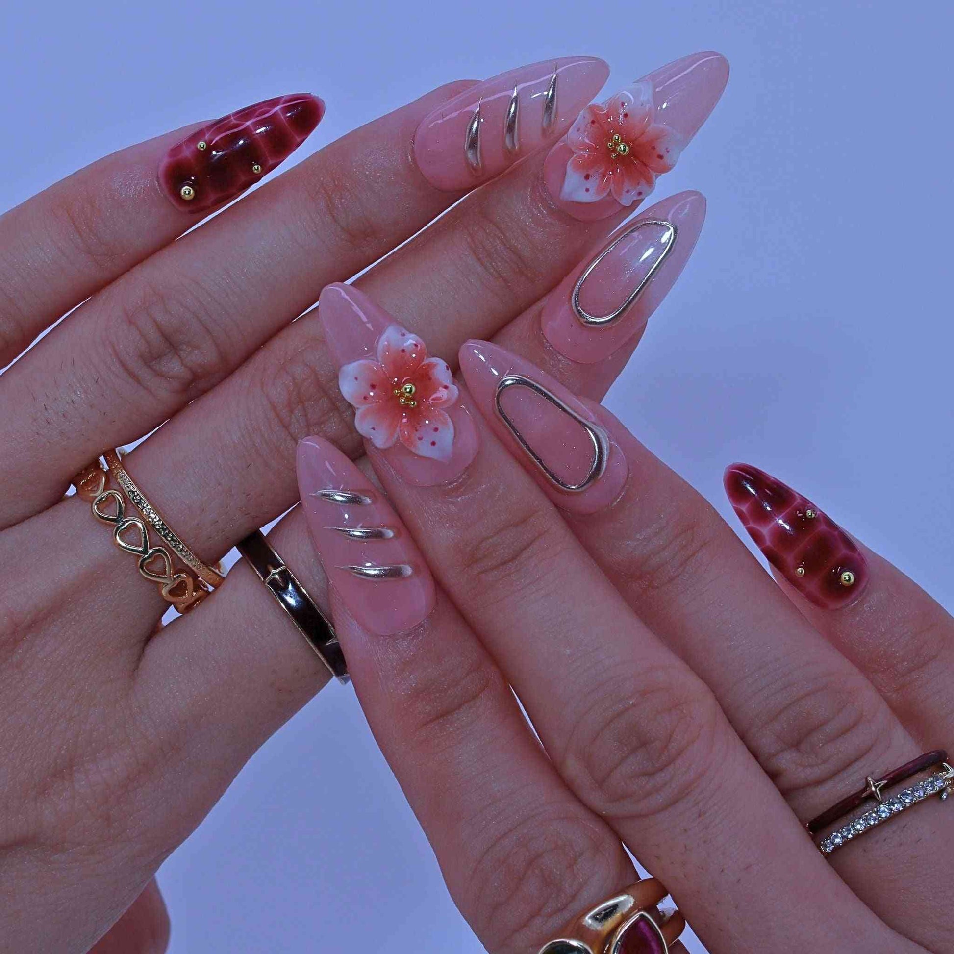 Close-up of a hand with decorative nails and rings on a blurred background by Tennail.