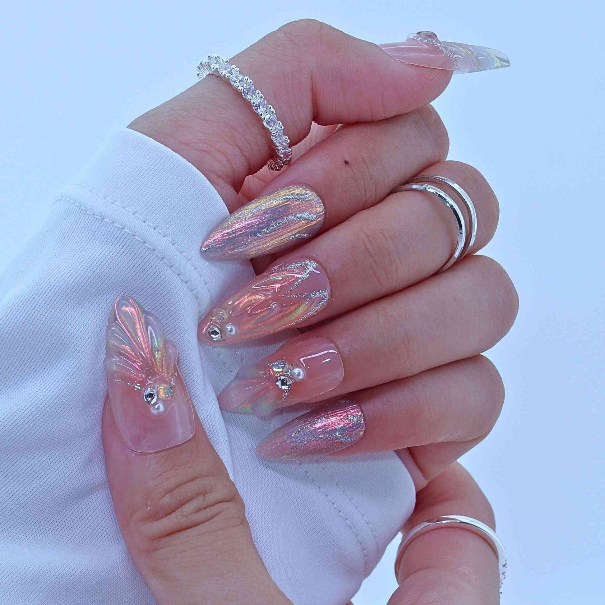 Hand with pink and silver nail design on a white background by Tennail.