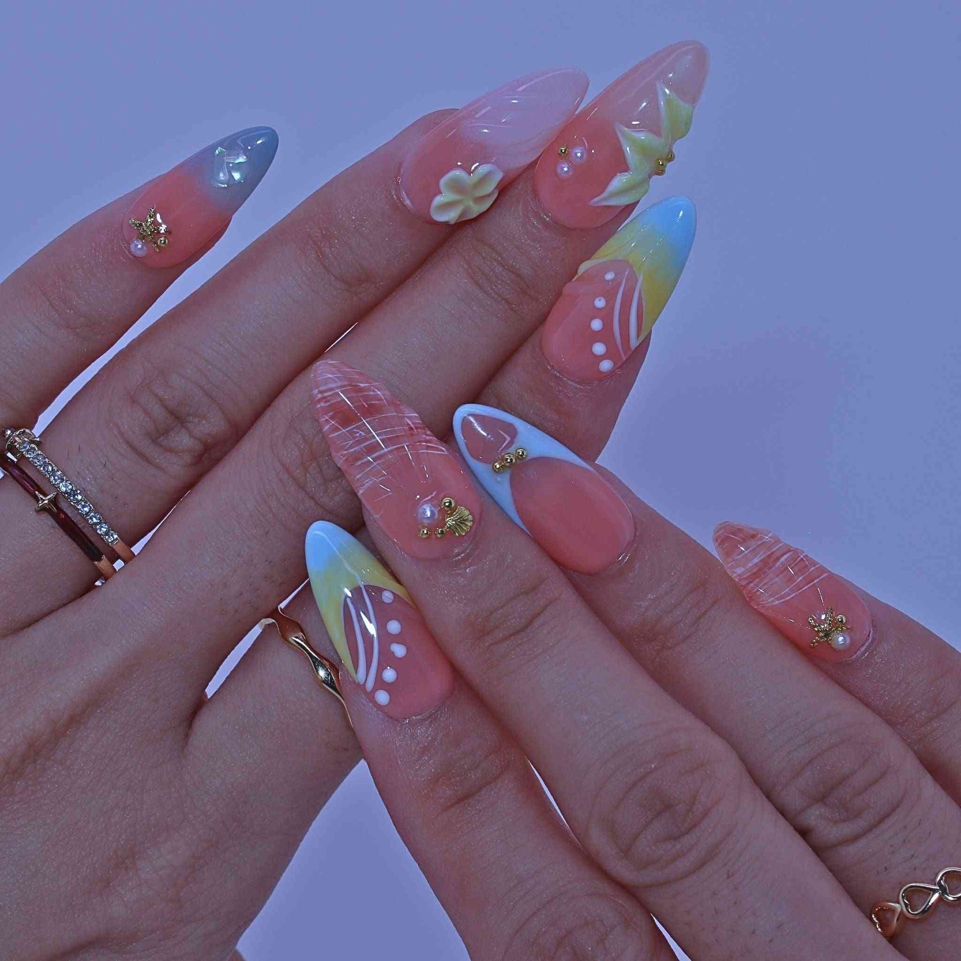 Close-up of a hand with colorful nail art , Coastal Bloom press on Nails with hand-painted florals, starfish accents, coastal hues by Tennial