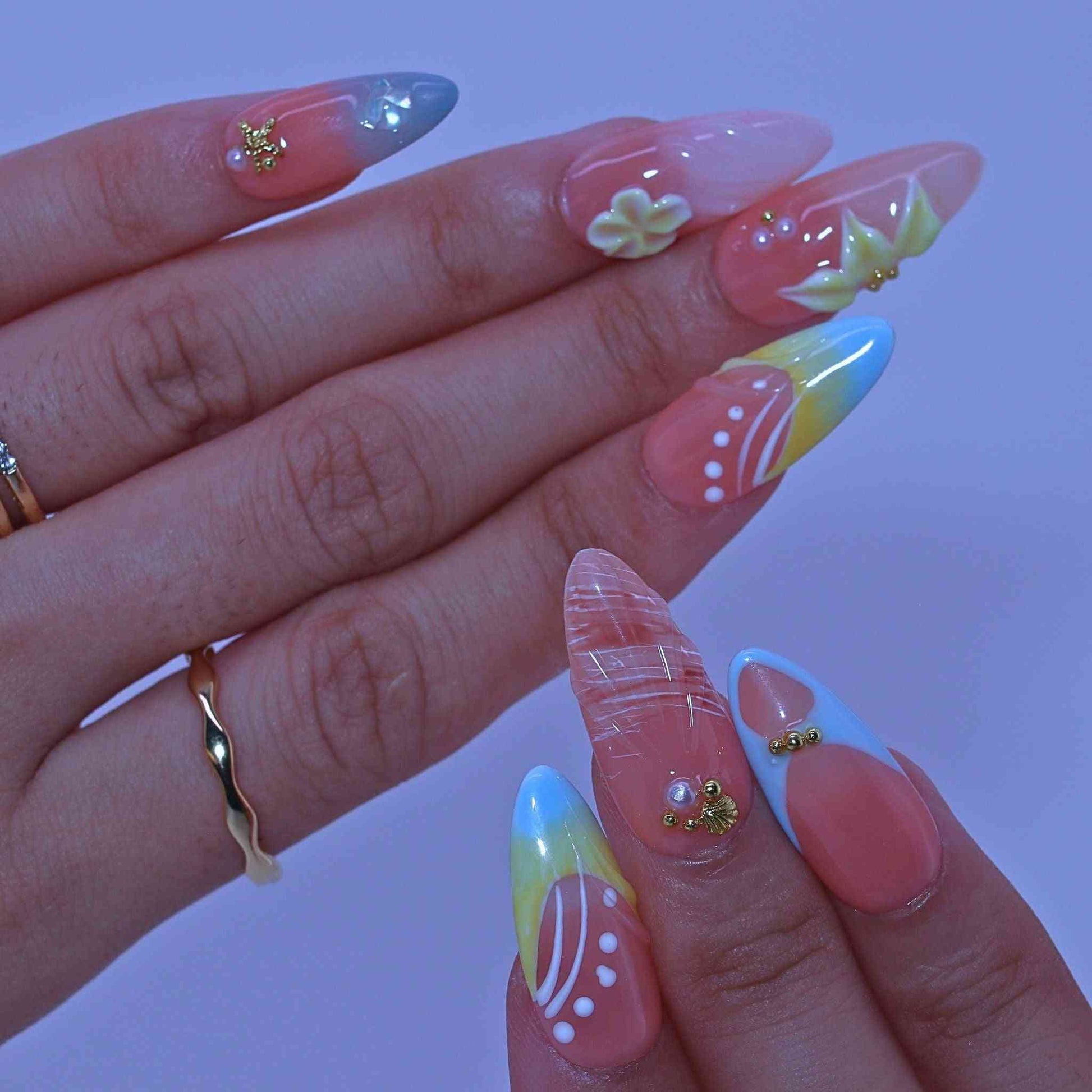 Close-up of a hand with colorful nail art  , Coastal Bloom press on Nails with hand-painted florals, starfish accents, coastal hues by Tennial