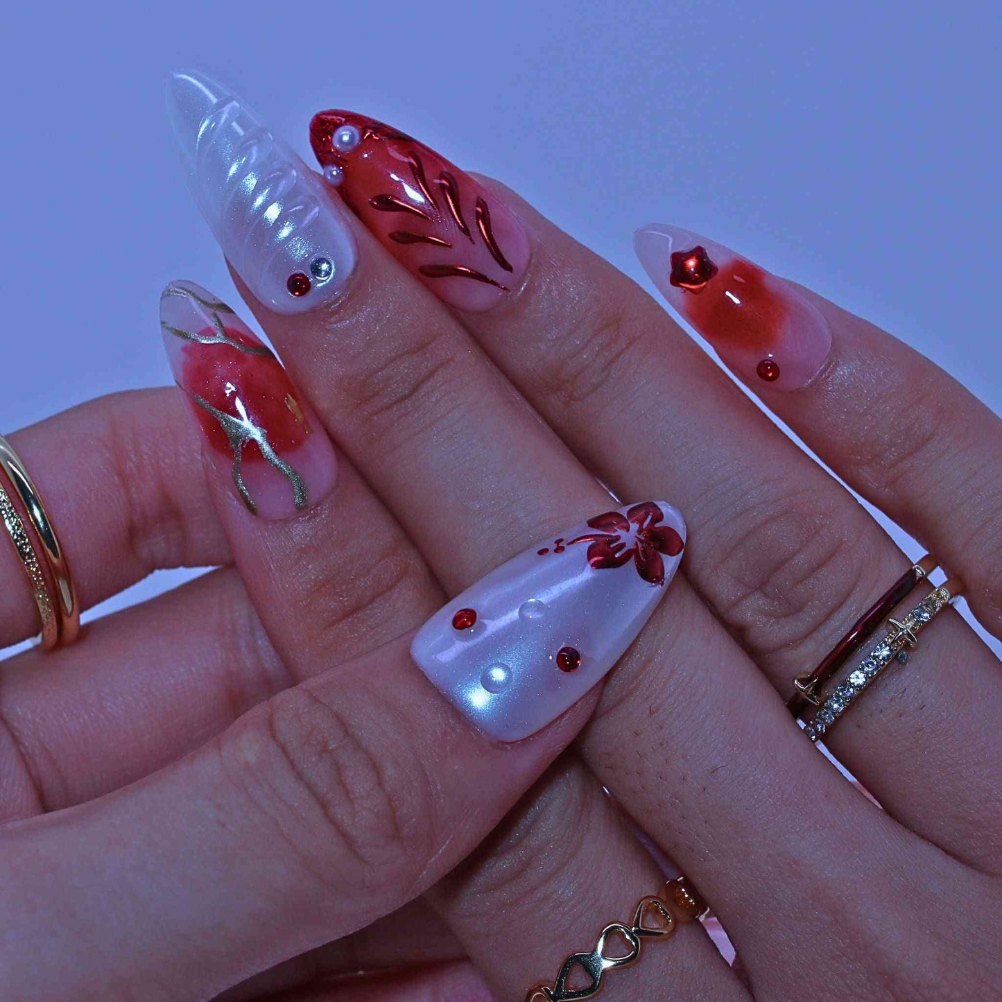Close-up of a hand with red and white nail art, Crimson Bloom press on Nails with hand-painted red florals, gradients, rhinestone accents by Tennailund