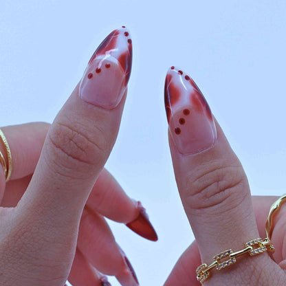 Close-up of a hand with marbled red and pink nail polish, Tropical Flowers Press on Nails with hand-painted florals, red gradients, delicate accents by Tennail.