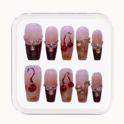 Close up of Cherry Blossom Glow handmade press-on nails showing deep wine red color and sparkling rhinestone decorations designed to brighten skin tone.