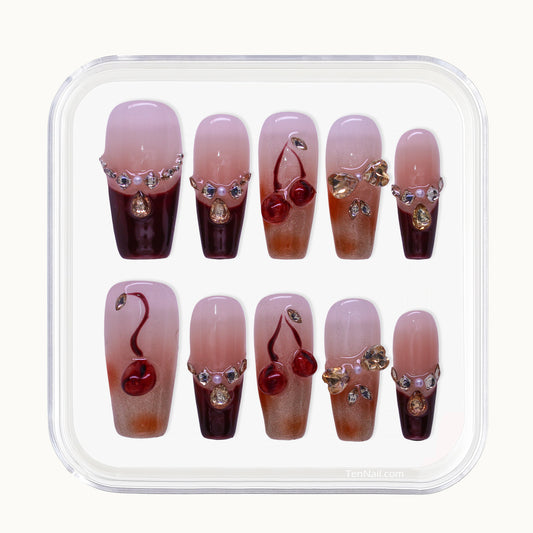 Close up of Cherry Blossom Glow handmade press-on nails showing deep wine red color and sparkling rhinestone decorations designed to brighten skin tone.