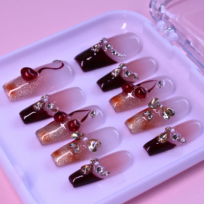 Close up of Cherry Blossom Glow handmade press-on nails showing deep wine red color and sparkling rhinestone decorations designed to brighten skin tone.