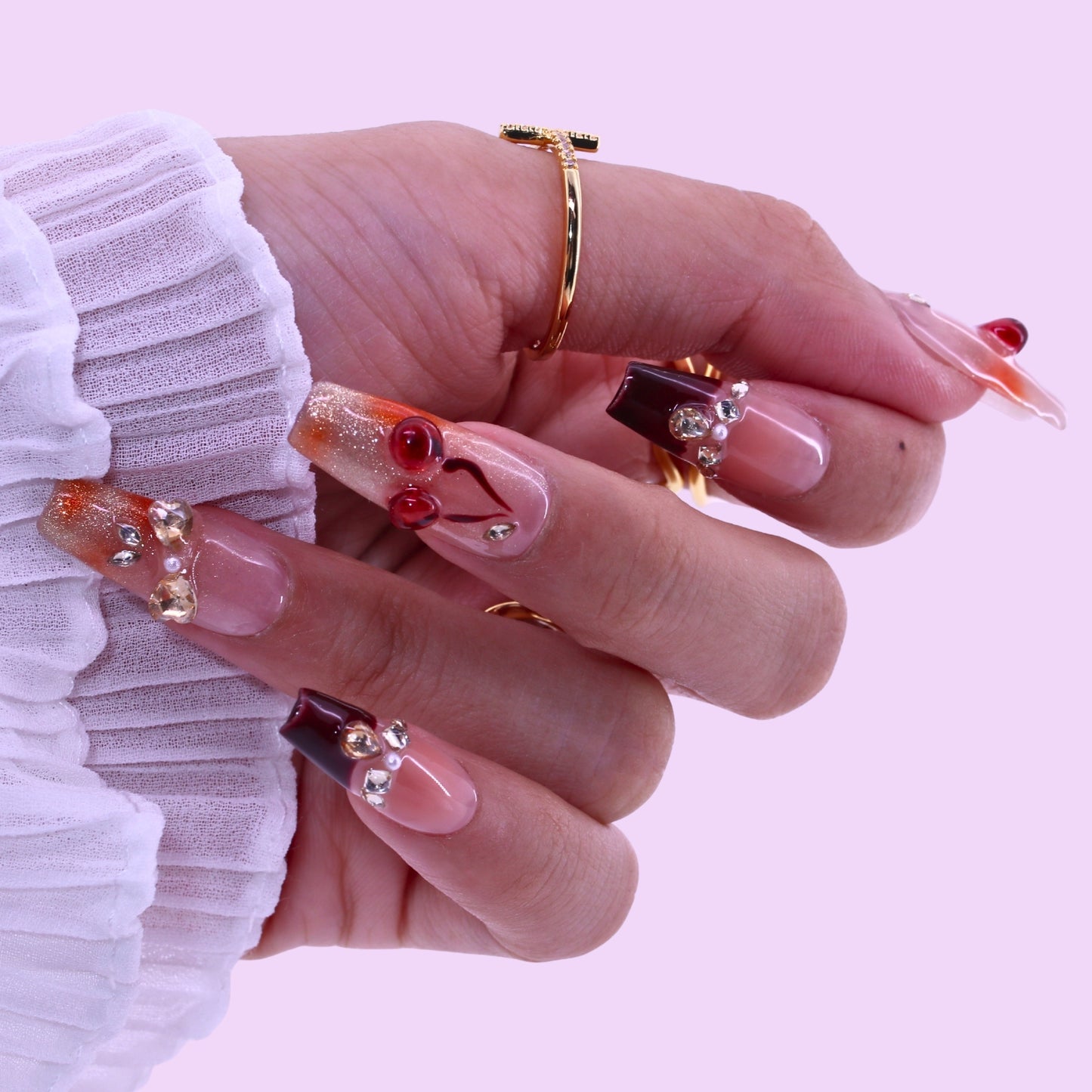 T2511N059 Cherry Blossom Glow Nails byTenNail,Close-up of a hand with decorative nails on a light pink background