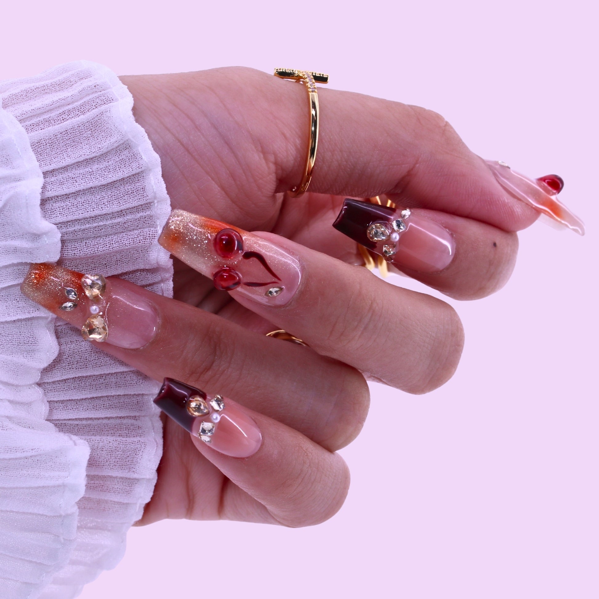 T2511N059 Cherry Blossom Glow Nails byTenNail,Close-up of a hand with decorative nails on a light pink background