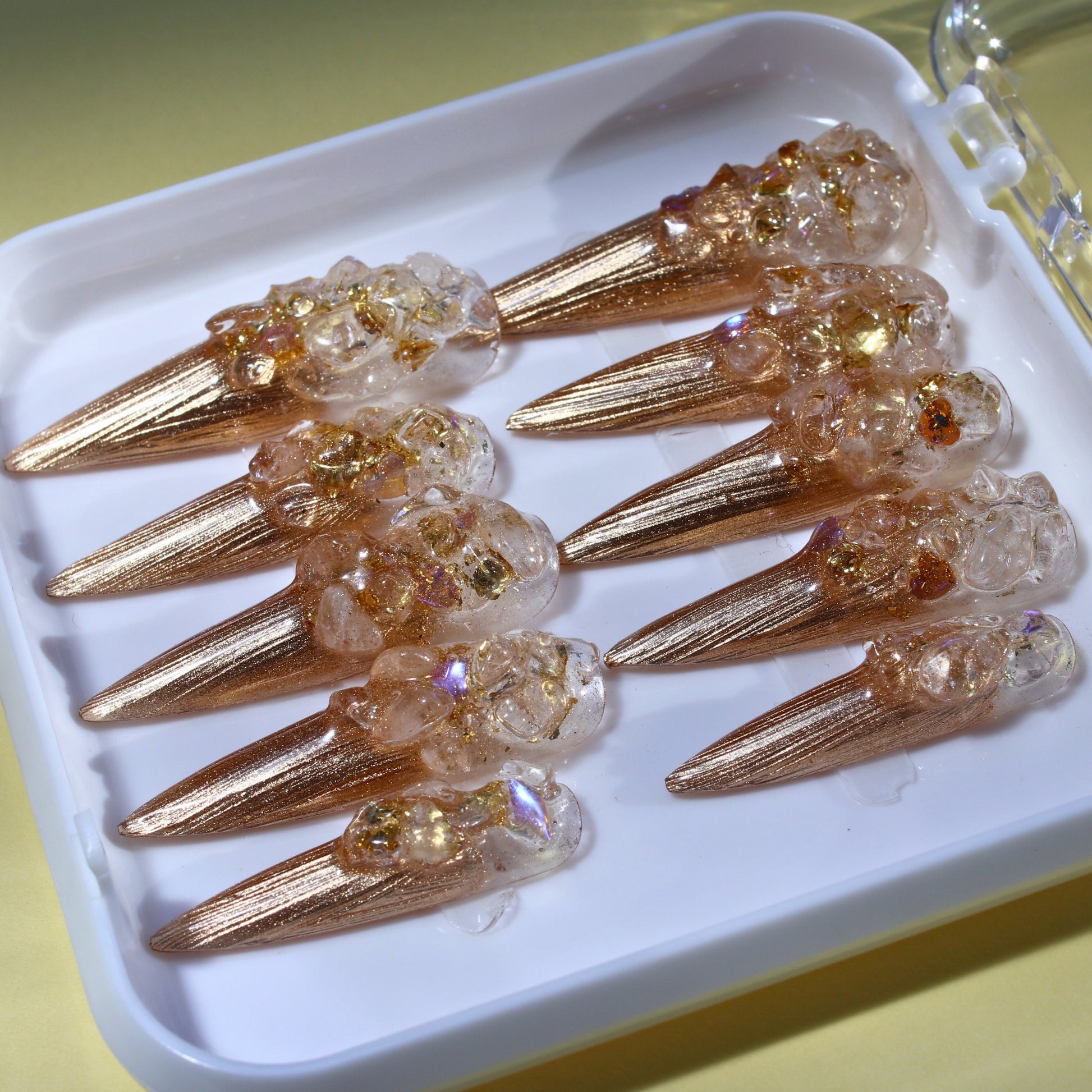 Long Stiletto press-on nails in metallic gold with a clear 3D crushed crystal texture.
