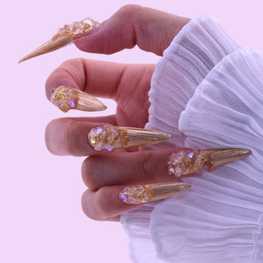 Hand with gold and crystal nail art holding a decorative item , Tennail handmade press on nails.