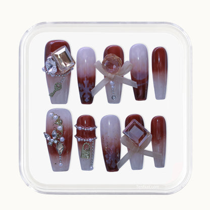 Long Coffin press-on nails with Maillard brown Ombré, rhinestone, and pearl 3D accents.