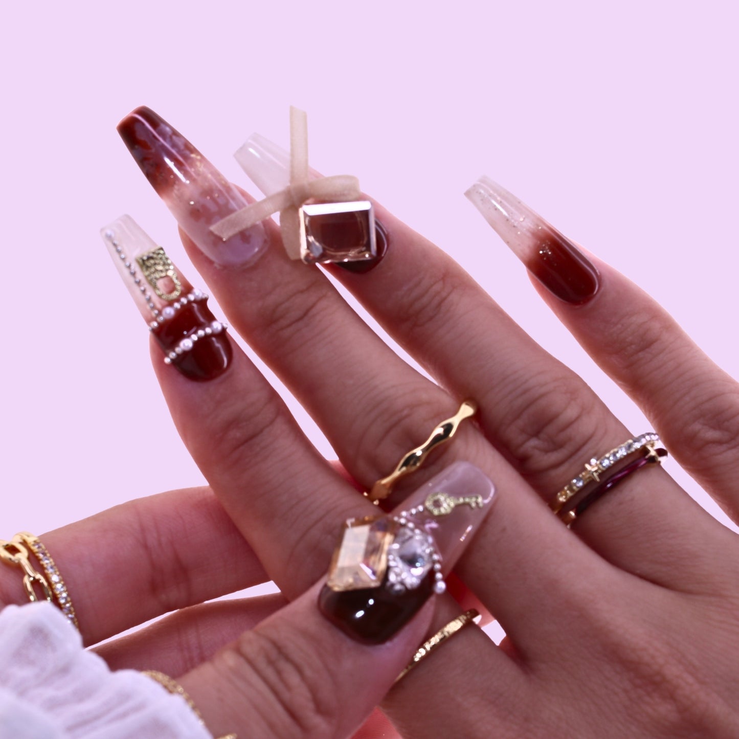 Hand with long, dark nail polish wearing multiple rings, Tennail handmade press on nails.