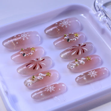 Medium Almond press-on nails with nude blush color, hand painted Christmas trees, and glitter.
