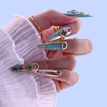 Hand holding decorative hair pins with gemstones against a light blue background, Tennail handmade press on nails.