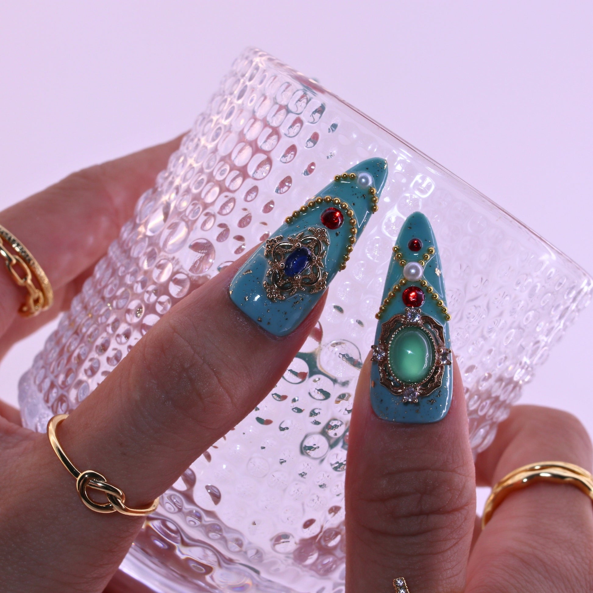 Decorative turquoise hair clips with gemstones held by a hand , Tennail handmade press on nails.