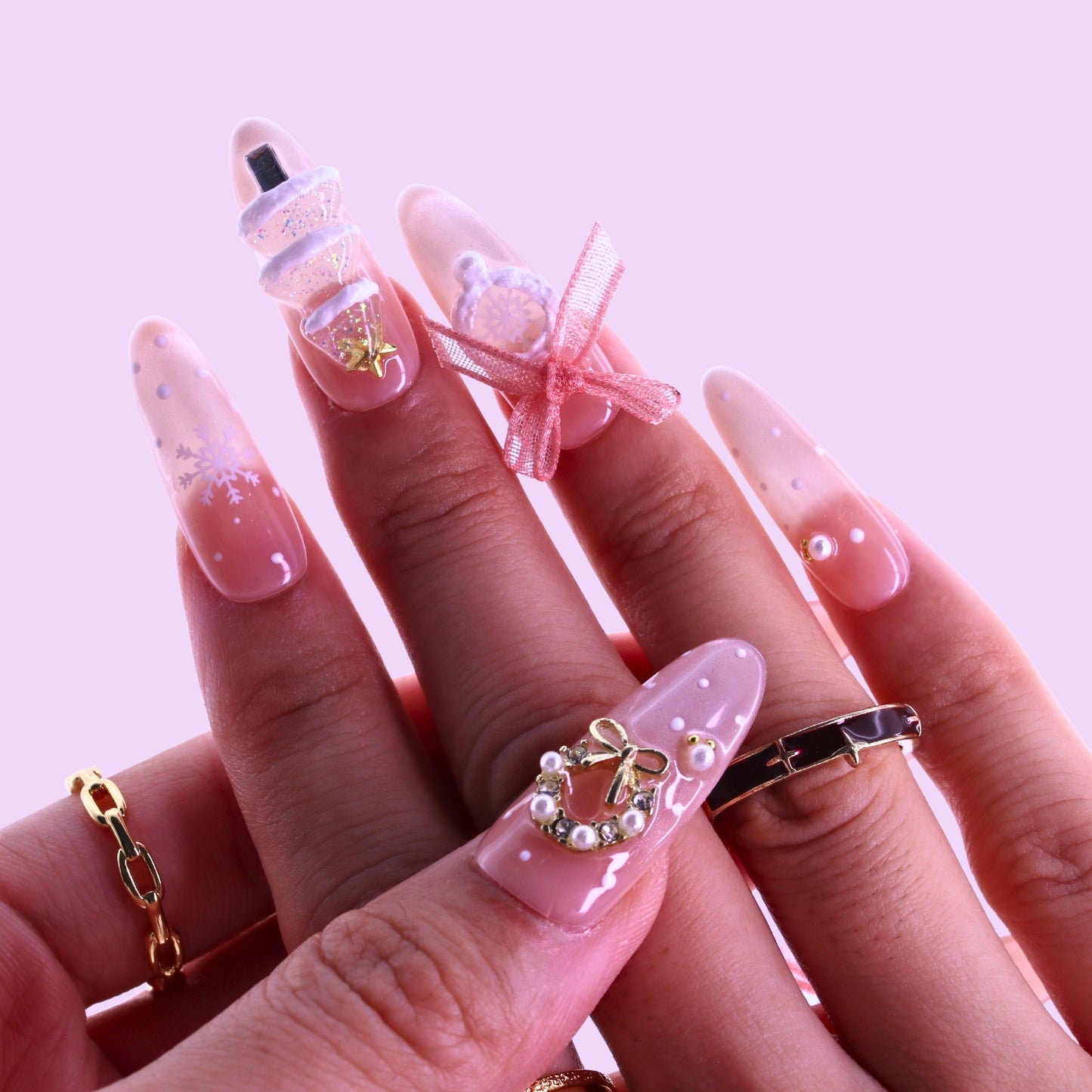 Close-up of hands with pink nail art featuring bow designs, Tennail handmade press on nails.