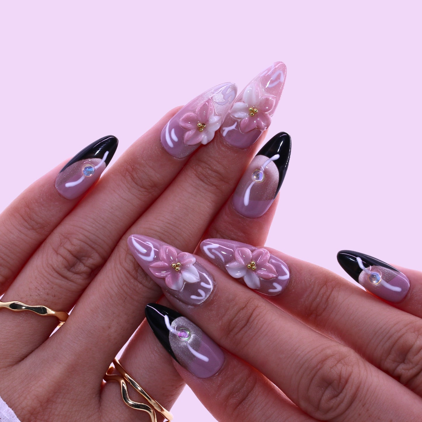 Hand with decorative nails featuring flowers and black accents, Tennail handmade press on nails.
