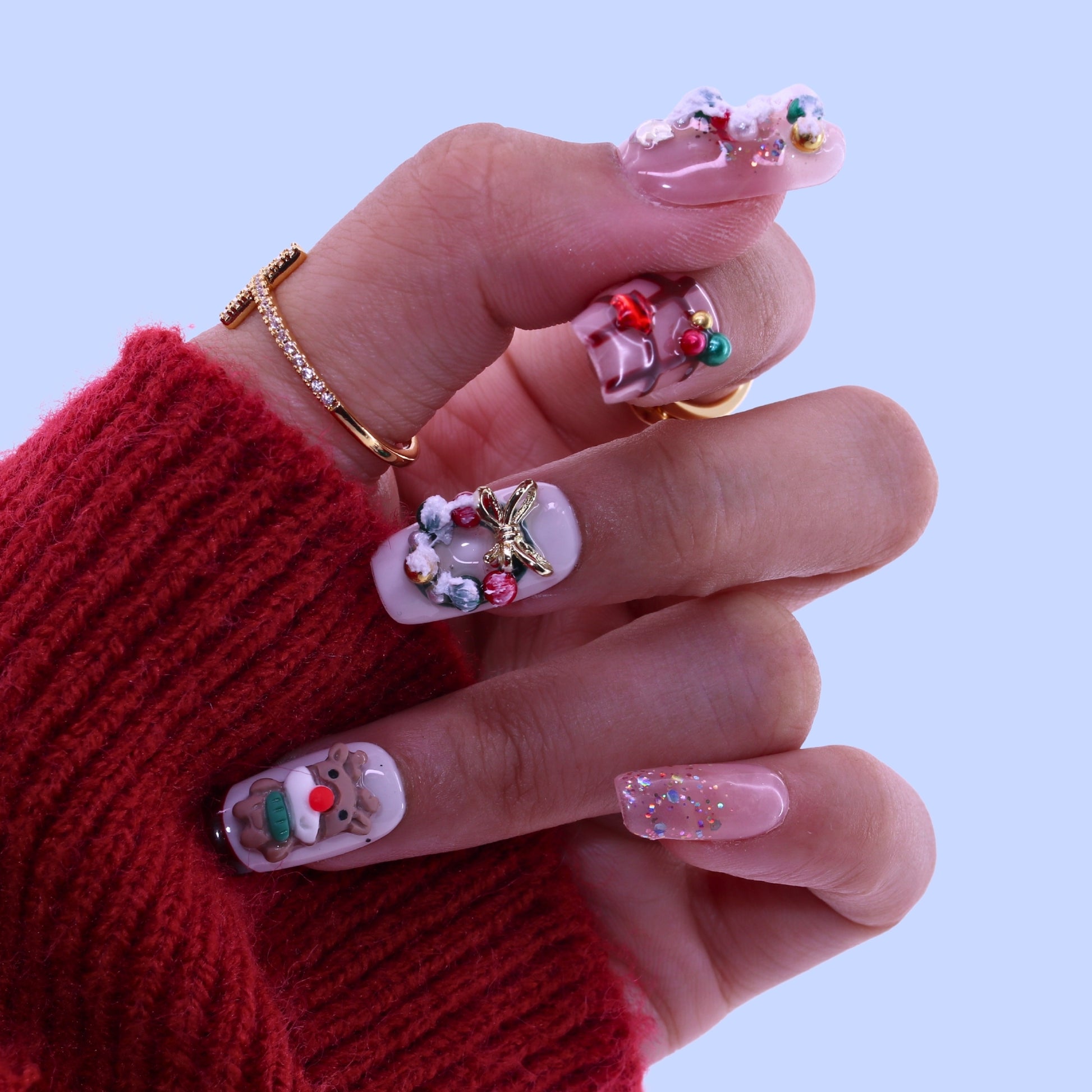 Hand with decorated nails wearing a red sweater, Tennail handmade press on nails.