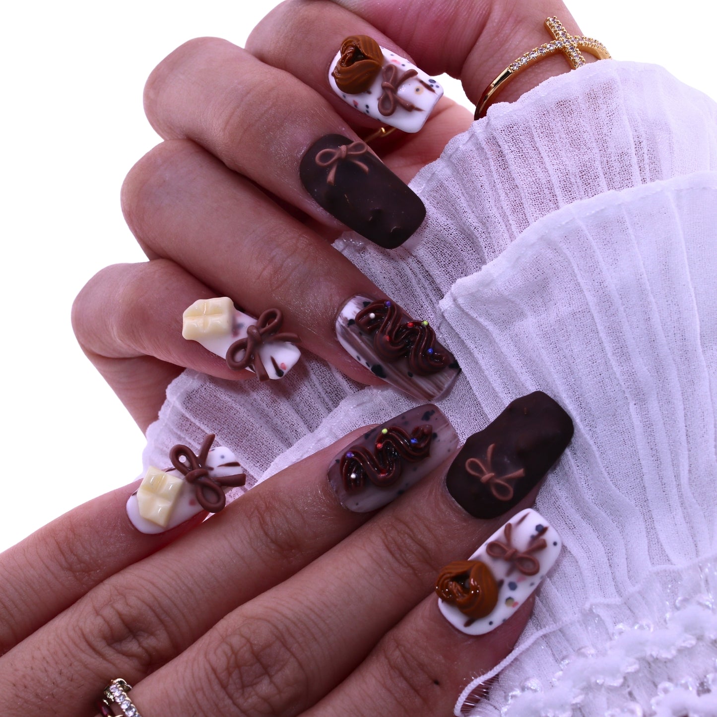 Close-up of a hand with intricately designed nails featuring chocolate-themed decorations, Tennail handmade press on nails.